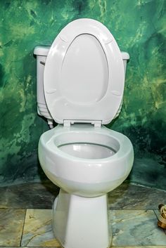 a white toilet sitting in a bathroom next to a green wall