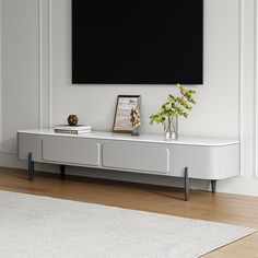 a white entertainment center with a black screen mounted on the wall