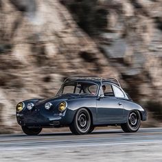 an old black car driving down the road