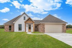 a single story house in the middle of a grassy area with a driveway and two garages