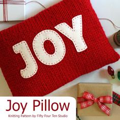 a red knitted pillow with the word joy on it next to some crafting supplies