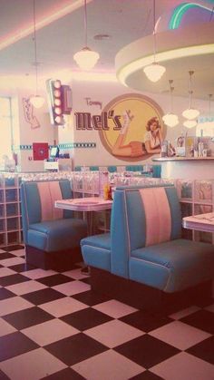 the interior of a diner with checkered flooring and blue booth booths, white walls, and neon lights