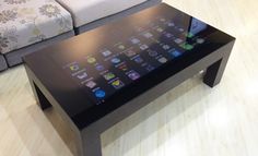 a coffee table with an ipad on it in front of a couch and ottomans