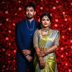 a man and woman standing next to each other in front of a flowery wall