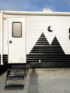 a white trailer with mountains painted on it's side and stairs leading up to the door