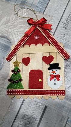 a christmas ornament hanging on a wall with a tree and snowman in it