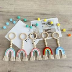 four wooden rings with tassels and beads on a wood table next to an envelope