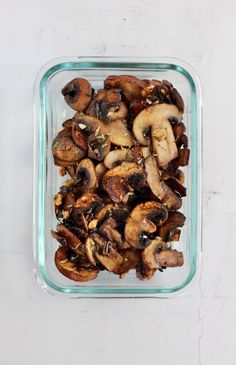 sliced mushrooms in a glass dish on a white surface