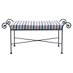 a bench that is sitting on top of a metal frame and has striped seat cushion