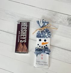 a chocolate bar next to a snowman ornament on a white wooden surface