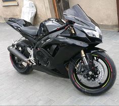 a black motorcycle parked on the street next to a building with a red and yellow stripe around it