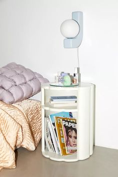 a magazine rack with magazines on it next to a bed