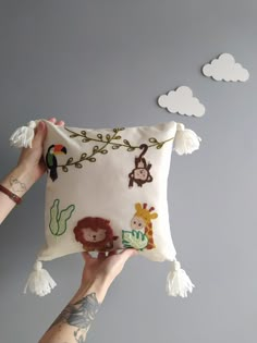 someone holding up a pillow with animals on it