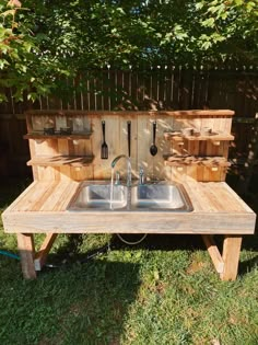 an outdoor sink made out of pallet wood with utensils hanging from it