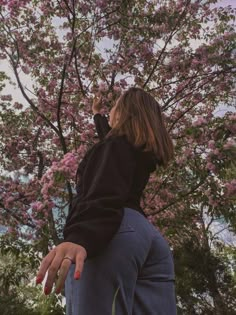 a woman standing in front of a tree with pink flowers