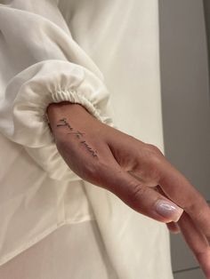 a woman's left hand with a small tattoo on the middle of her arm