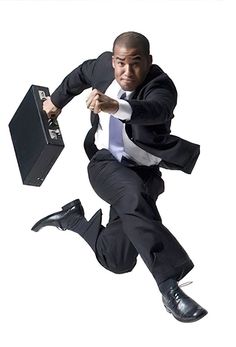 a man in a suit and tie jumping into the air with a briefcase on his back