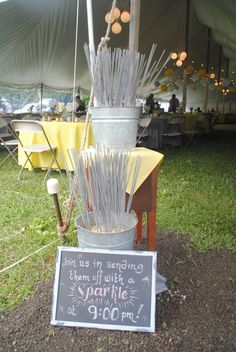 a sign that is sitting in the dirt next to a bucket with sticks sticking out of it