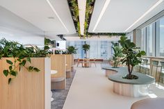 an office with plants on the walls and tables in the middle, along with chairs