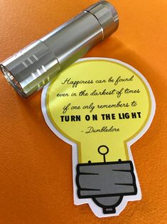 a light bulb sticker sitting on top of an orange table next to a flashlight