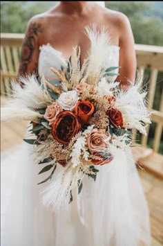 a bride holding a bridal bouquet with feathers and flowers on it's back