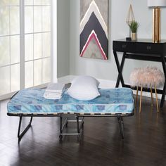 a bed sitting on top of a hard wood floor next to a table and chair