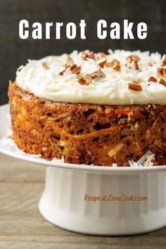 carrot cake with cream cheese frosting and nuts on top, sitting on a white plate