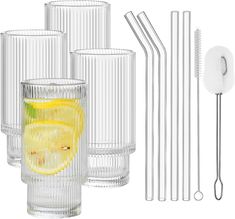 a set of four drinking glasses with straws and lemon slices in front of them