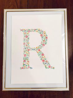 the letter r is made out of flowers and has been framed in a white frame