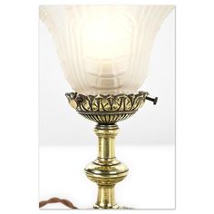 an antique brass table lamp with a white glass shade on it's top and base