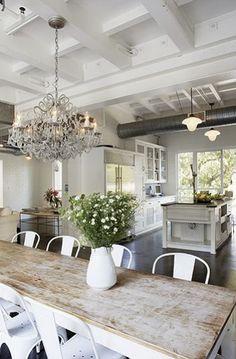 a dining room table with white chairs and a chandelier hanging from the ceiling