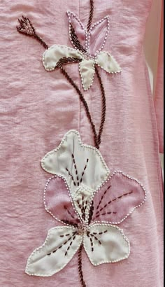 an embroidered pink dress with white flowers on it