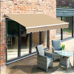 an outdoor patio area with chairs, table and awning on the side of a brick building