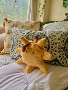 a stuffed animal laying on top of a bed next to pillows and pillowcases