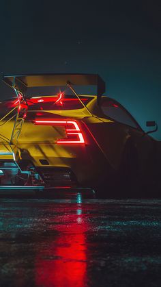 the back end of a yellow sports car with its tail lights on at night time