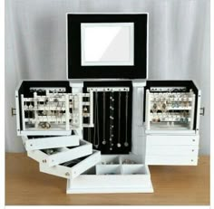 an open jewelry box sitting on top of a wooden table next to a white dresser