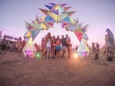 a group of people standing in front of a colorful sculpture