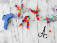 scissors, sprinkles and glue on a marble surface with the word spelled out