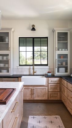 a kitchen with wooden cabinets and black counter tops, along with a white rug on the floor