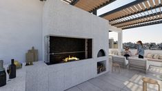 two people sitting on a patio with a fire place in the middle and an outdoor fireplace