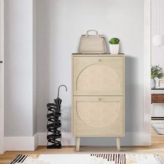 a white cabinet with an umbrella and plant on top in the corner of a room