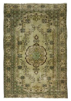 an antique rug with green and beige colors