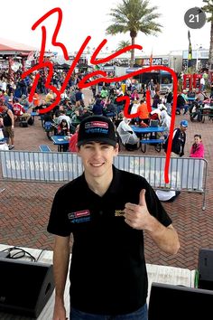 a man giving the thumbs up sign in front of an outdoor event with people sitting and standing around