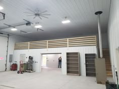 the inside of a building with two men standing in it's doorways and ceiling fans