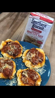 four mini pizzas on a blue plate next to a bag of biscuit mix