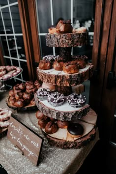 a table topped with lots of different types of doughnuts on top of wooden slices