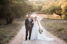 a bride and groom walking down a dirt road