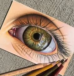 a drawing of an eye with colored pencils next to it