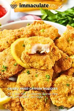 a plate full of fried fish nuggets with lemon wedges