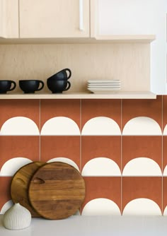 a wooden cutting board sitting on top of a counter next to a vase and bowl